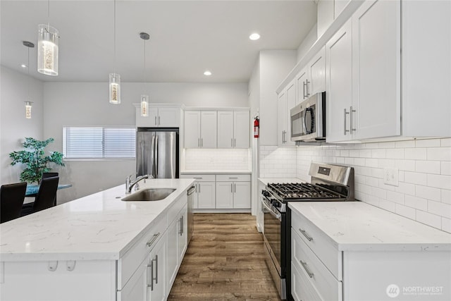 7724 16th Ave SW, Seattle, WA 98106 - kitchen featuring appliances with stainless steel finishes, a sink, wood finished floors, white cabinetry, and recessed lighting
