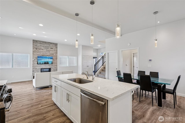 7724 16th Ave SW, Seattle, WA 98106 - kitchen with stainless steel appliances, a sink, light wood-style floors, a large fireplace, and open floor plan