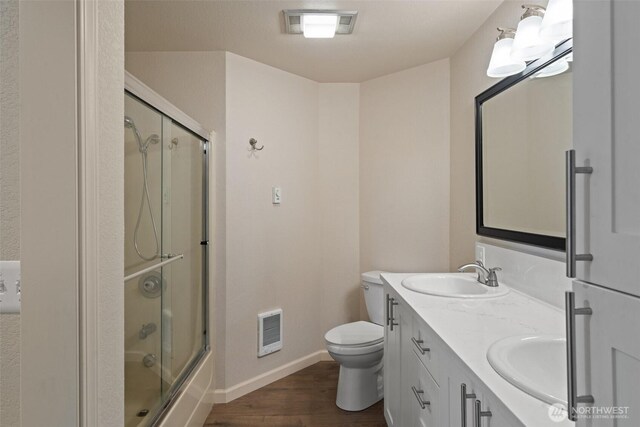 807 W Fir St, Sequim, WA 98382 - bathroom featuring baseboards, heating unit, wood finished floors, toilet, and double vanity