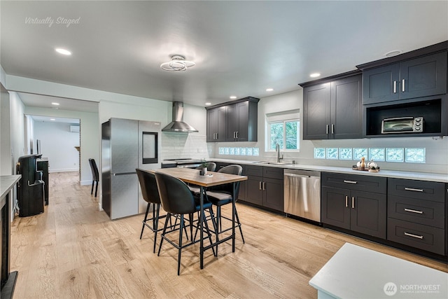 925 Front St S, Issaquah, WA 98027 - kitchen featuring stainless steel appliances, wall chimney exhaust hood, light countertops, light wood-type flooring, and recessed lighting