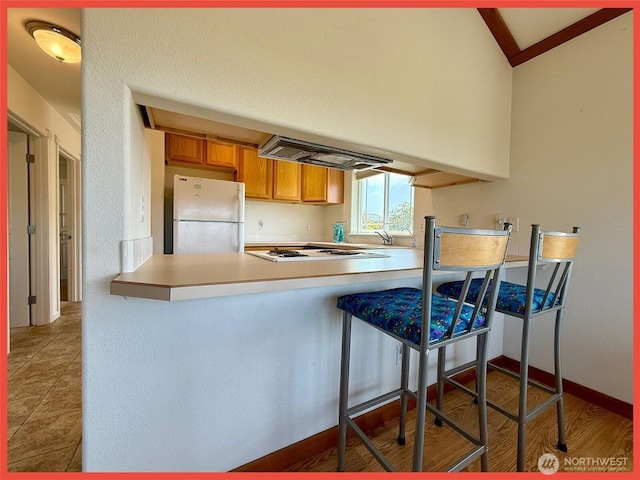 486 Winlock St, Ocean Shores, WA 98569 - kitchen featuring white appliances, brown cabinetry, a peninsula, lofted ceiling, and a breakfast bar