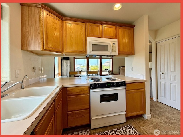 486 Winlock St, Ocean Shores, WA 98569 - kitchen with white appliances, light tile patterned floors, brown cabinetry, light countertops, and a peninsula