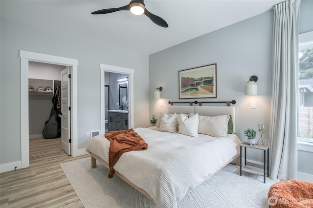 366 Lake View Loop NE, Ocean Shores, WA 98569 - bedroom with light wood-style floors, a spacious closet, baseboards, ensuite bathroom, and a ceiling fan