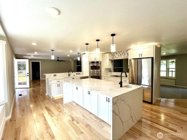 4012 267th St E, Spanaway, WA 98387 - kitchen with stainless steel appliances, a peninsula, a sink, light wood-style floors, and a textured ceiling