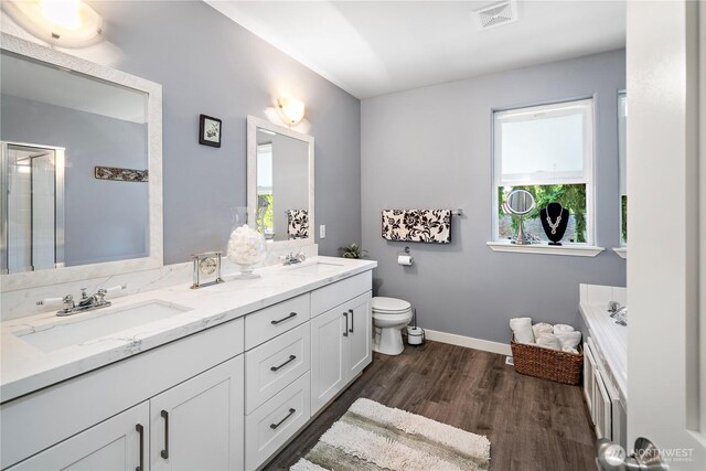 1314 N 182nd Pl, Shoreline, WA 98133 - bathroom featuring double vanity, wood finished floors, a garden tub, toilet, and a shower with shower door