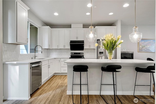 13421 Admiralty Way Unit A-2, Lynnwood, WA 98087 - kitchen featuring appliances with stainless steel finishes, a breakfast bar area, decorative backsplash, white cabinetry, and recessed lighting