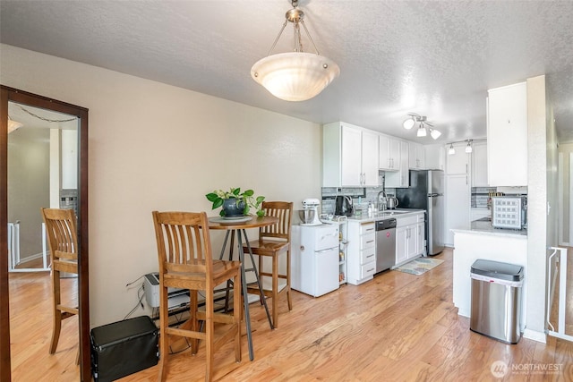 813 S 227th Pl Unit 5, Des Moines, WA 98198 - kitchen featuring stainless steel appliances, light countertops, white cabinetry, a textured ceiling, and tasteful backsplash