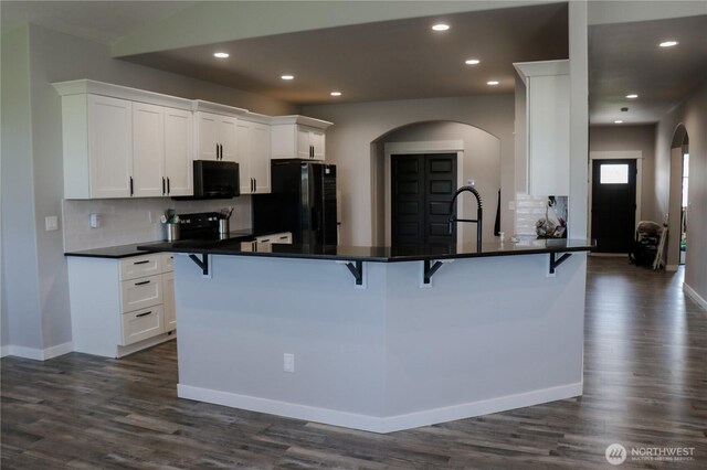 6354 Murray Way NE, Moses Lake, WA 98837 - kitchen featuring black appliances, arched walkways, a breakfast bar, dark countertops, and recessed lighting