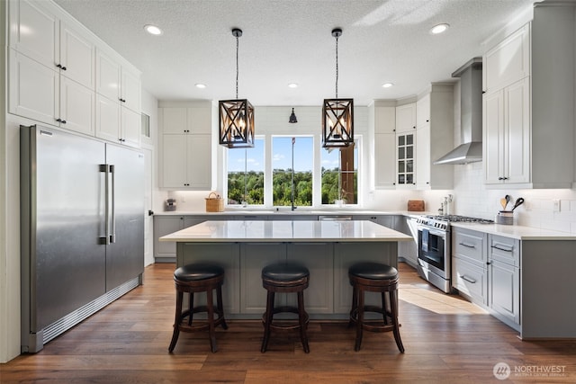 19428 NE 259th St S, Battle Ground, WA 98604 - kitchen with stainless steel appliances, wall chimney range hood, a center island, a kitchen bar, and tasteful backsplash