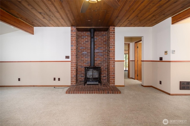 16757 Chilberg Ave, La Conner, WA 98257 - unfurnished living room featuring carpet flooring, a wood stove, wooden ceiling with exposed beams, ceiling fan, and baseboards