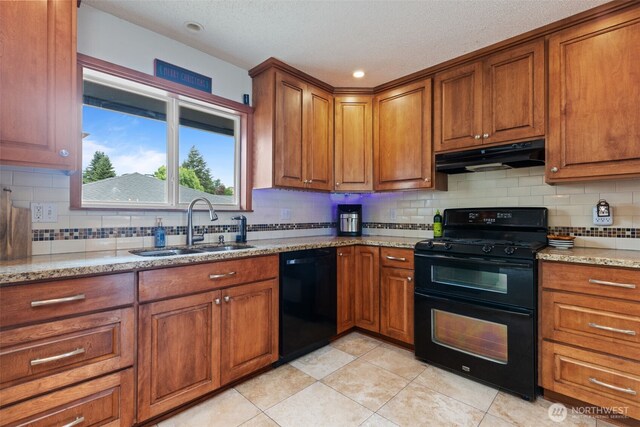1350 S Woodlawn St, Tacoma, WA 98465 - kitchen with black appliances, under cabinet range hood, brown cabinetry, light stone countertops, and a textured ceiling