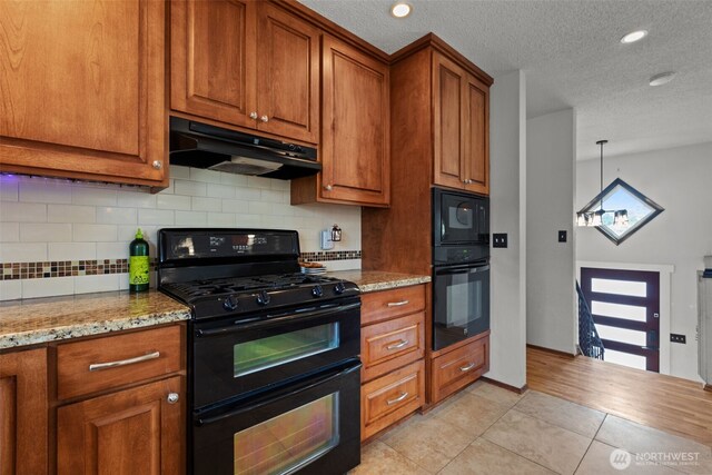 1350 S Woodlawn St, Tacoma, WA 98465 - kitchen featuring black appliances, under cabinet range hood, brown cabinetry, light tile patterned floors, and a textured ceiling