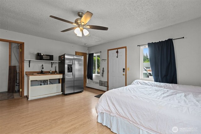 1350 S Woodlawn St, Tacoma, WA 98465 - bedroom with stainless steel fridge with ice dispenser, a textured ceiling, light wood-type flooring, and a ceiling fan