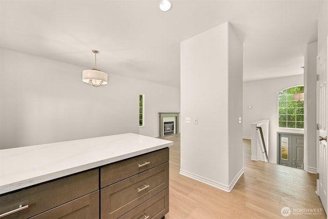 1999 Governor Rd, Bellingham, WA 98229 - kitchen featuring light wood-style flooring, light stone counters, hanging light fixtures, a fireplace, and dark brown cabinets