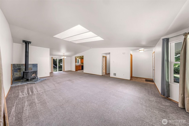 4441 Forgotten Ln, Clinton, WA 98236 - unfurnished living room with lofted ceiling, carpet flooring, a wood stove, and a skylight