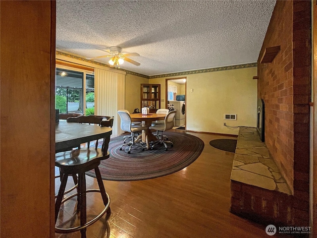2208 Sandra Ave, Centralia, WA 98531 - dining area featuring wood finished floors, a textured ceiling, a brick fireplace, ceiling fan, and ornamental molding