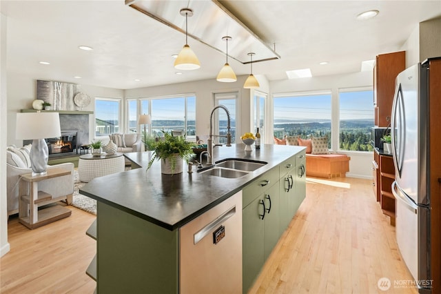 13712 SE 44th St, Bellevue, WA 98006 - kitchen with appliances with stainless steel finishes, a sink, dark countertops, light wood-style floors, and a center island with sink