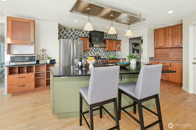 13712 SE 44th St, Bellevue, WA 98006 - kitchen featuring appliances with stainless steel finishes, wall chimney range hood, dark countertops, decorative backsplash, and light wood-type flooring