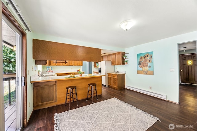10320 46th Ave SE, Olympia, WA 98513 - kitchen with a baseboard radiator, white refrigerator with ice dispenser, brown cabinets, a peninsula, and dark wood-style floors
