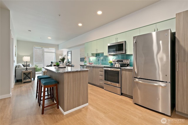 1085 103rd Ave NE Unit 203, Bellevue, WA 98004 - kitchen featuring appliances with stainless steel finishes, a center island, light wood finished floors, a breakfast bar, and recessed lighting