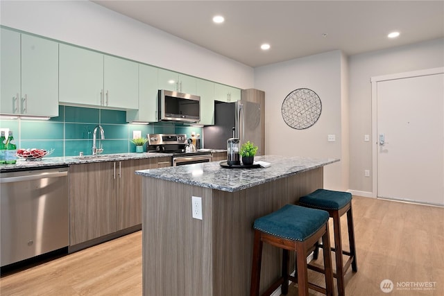 1085 103rd Ave NE Unit 203, Bellevue, WA 98004 - kitchen with appliances with stainless steel finishes, a kitchen breakfast bar, a sink, light wood-style floors, and recessed lighting