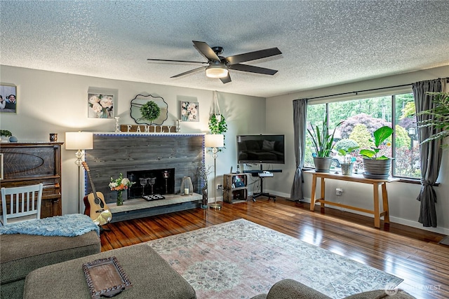5613 89th Ave W, University Place, WA 98467 - living room featuring a fireplace with raised hearth, ceiling fan, wood-type flooring, a textured ceiling, and baseboards