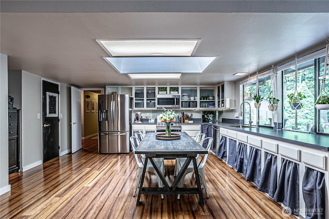 5613 89th Ave W, University Place, WA 98467 - kitchen with appliances with stainless steel finishes, wood finished floors, dark countertops, a sink, and open shelves