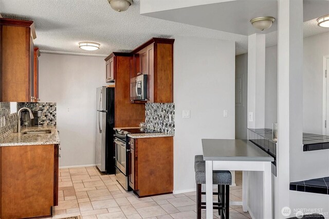 4561 Lake Washington Blvd NE Unit 303, Kirkland, WA 98033 - kitchen with appliances with stainless steel finishes, a sink, backsplash, light stone counters, and a textured ceiling