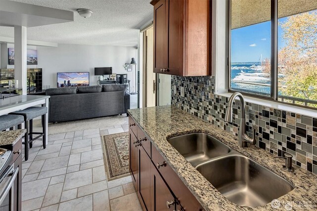 4561 Lake Washington Blvd NE Unit 303, Kirkland, WA 98033 - kitchen with a sink, decorative backsplash, light stone countertops, a textured ceiling, and open floor plan