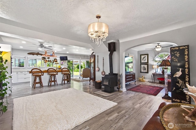 10 E Sunny Sands Rd, Cathlamet, WA 98612 - living room with a ceiling fan, a textured ceiling, a wood stove, arched walkways, and wood finished floors