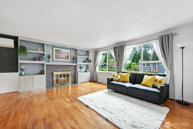2433 199th Pl SW, Lynnwood, WA 98036 - living room with a wall mounted AC, wood finished floors, a fireplace with flush hearth, baseboards, and a textured ceiling