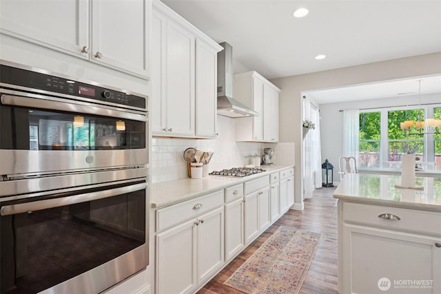 648 S Davis St, Buckley, WA 98321 - kitchen with stainless steel appliances, wall chimney range hood, light countertops, tasteful backsplash, and wood finished floors