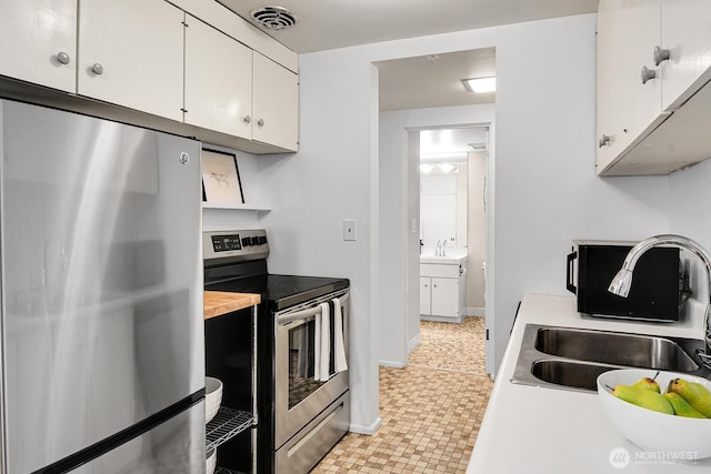 919 2nd Ave W Unit 103, Seattle, WA 98119 - kitchen with refrigerator, electric range, light countertops, and white cabinetry