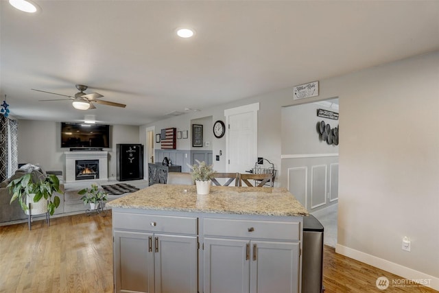 22506 SE 277th Pl, Maple Valley, WA 98038 - kitchen with a ceiling fan, light wood finished floors, a glass covered fireplace, and gray cabinets
