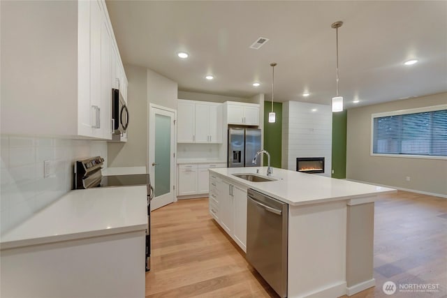18226 37th Ave E, Tacoma, WA 98446 - kitchen featuring stainless steel appliances, a sink, a large fireplace, light wood-style floors, and recessed lighting