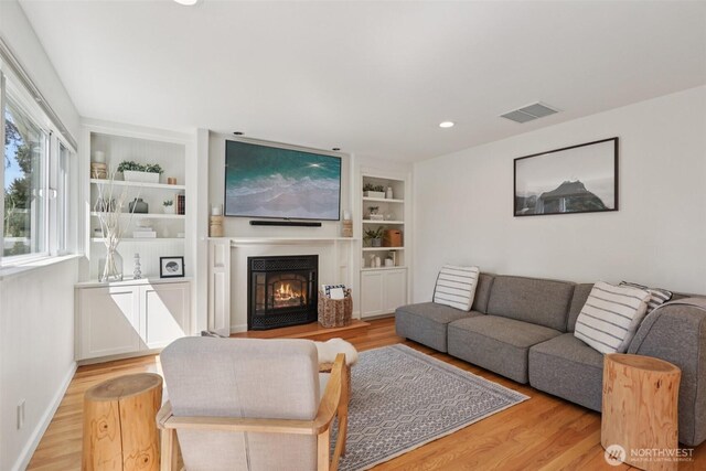 7511 230th Ave NE, Redmond, WA 98053 - living room featuring light wood finished floors, built in shelves, a warm lit fireplace, baseboards, and recessed lighting