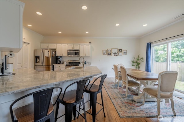 7615 14th St SE, Lake Stevens, WA 98258 - kitchen with appliances with stainless steel finishes, white cabinetry, recessed lighting, light wood finished floors, and light stone counters