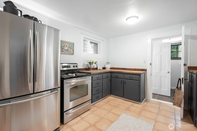 2560 Gilman Dr W, Seattle, WA 98119 - kitchen with stainless steel appliances, gray cabinetry, light tile patterned floors, and butcher block counters