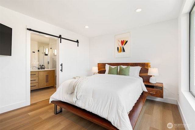 3240 32nd Ave W Unit B, Seattle, WA 98199 - bedroom with a barn door, light wood-style flooring, baseboards, recessed lighting, and ensuite bathroom