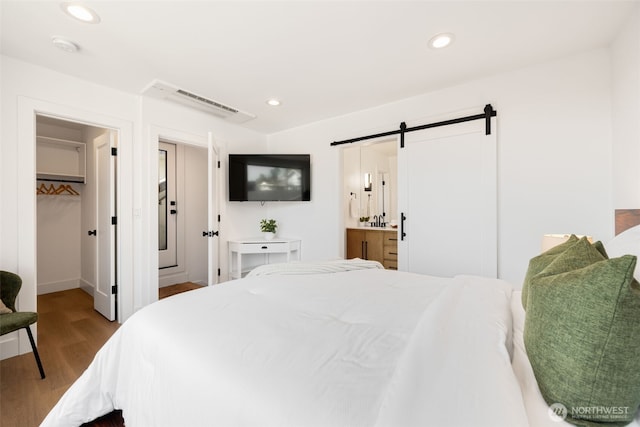 3240 32nd Ave W Unit B, Seattle, WA 98199 - bedroom with a barn door, wood finished floors, a walk in closet, recessed lighting, and ensuite bathroom