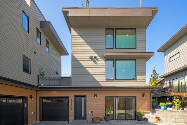 3240 32nd Ave W Unit B, Seattle, WA 98199 - rear view of house featuring a balcony, driveway, and an attached garage