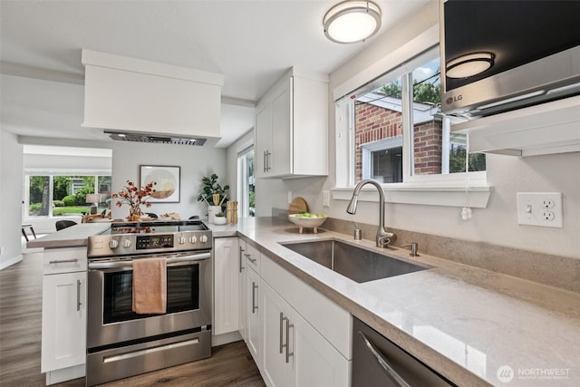 1022 N Anderson St, Tacoma, WA 98406 - kitchen featuring appliances with stainless steel finishes, a peninsula, dark wood-type flooring, white cabinetry, and custom exhaust hood