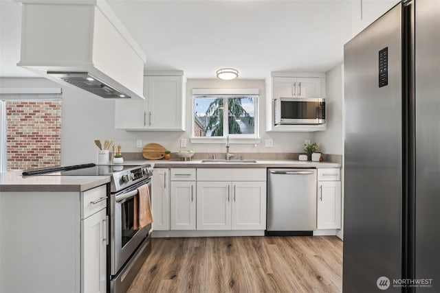 1022 N Anderson St, Tacoma, WA 98406 - kitchen with stainless steel appliances, premium range hood, white cabinets, light wood finished floors, and a peninsula
