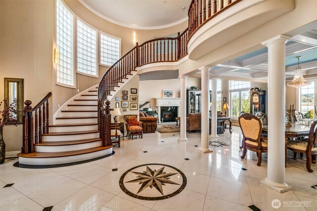 17765 Beach Dr NE, Lake Forest Park, WA 98155 - foyer featuring decorative columns, a towering ceiling, crown molding, stairway, and a glass covered fireplace