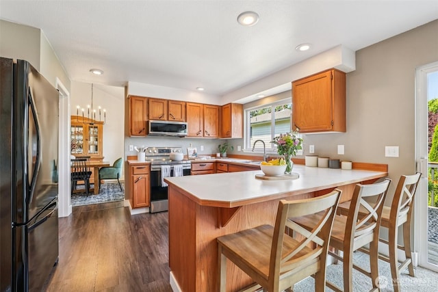 26820 NE 163rd St, Duvall, WA 98019 - kitchen featuring stainless steel appliances, a peninsula, brown cabinets, light countertops, and dark wood-style flooring