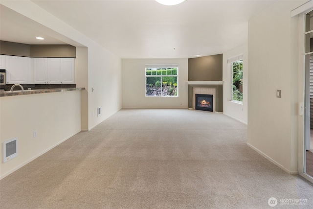 2220 132nd Ave SE Unit A220, Bellevue, WA 98005 - unfurnished living room with light carpet, plenty of natural light, a tiled fireplace, baseboards, and recessed lighting