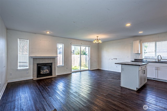 20007 17th Ave E, Spanaway, WA 98387 - kitchen with dark countertops, white cabinets, open floor plan, a kitchen island, and baseboards
