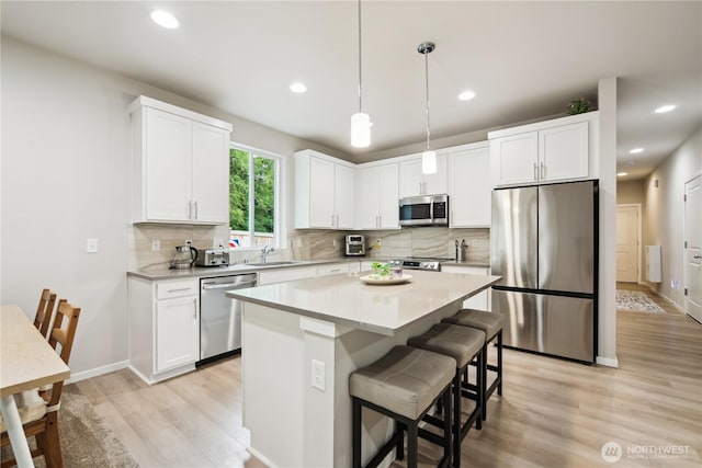 4305 23rd Ct NE, Olympia, WA 98516 - kitchen featuring appliances with stainless steel finishes, light wood-style flooring, a sink, backsplash, and white cabinets