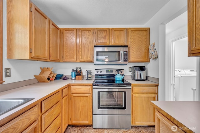 2779 Maple Tree Ln, Camano Island, WA 98282 - kitchen featuring appliances with stainless steel finishes, washing machine and clothes dryer, light countertops, and a sink