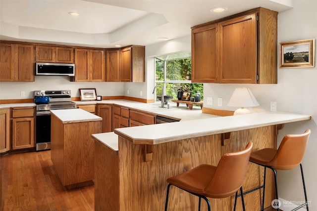 4624 SW 329th Way, Federal Way, WA 98023 - kitchen with stainless steel appliances, a sink, brown cabinetry, light countertops, and dark wood-style floors